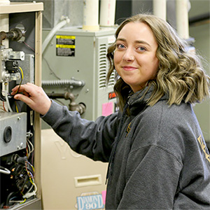 Photo of Kailey Forliti working on furnace in SCC lab