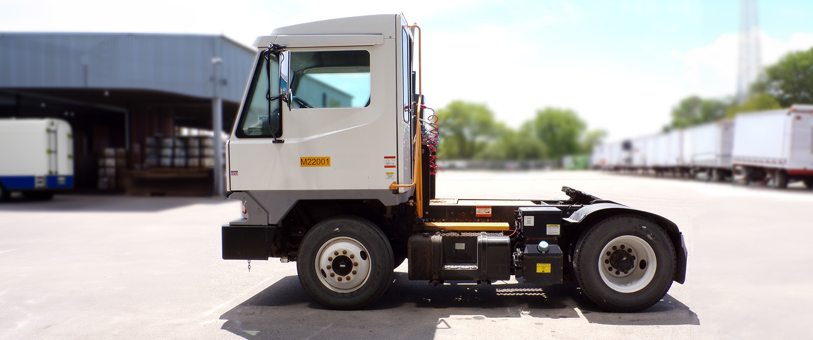 Yard truck parked in warehouse parking lot surrounded by trailers.