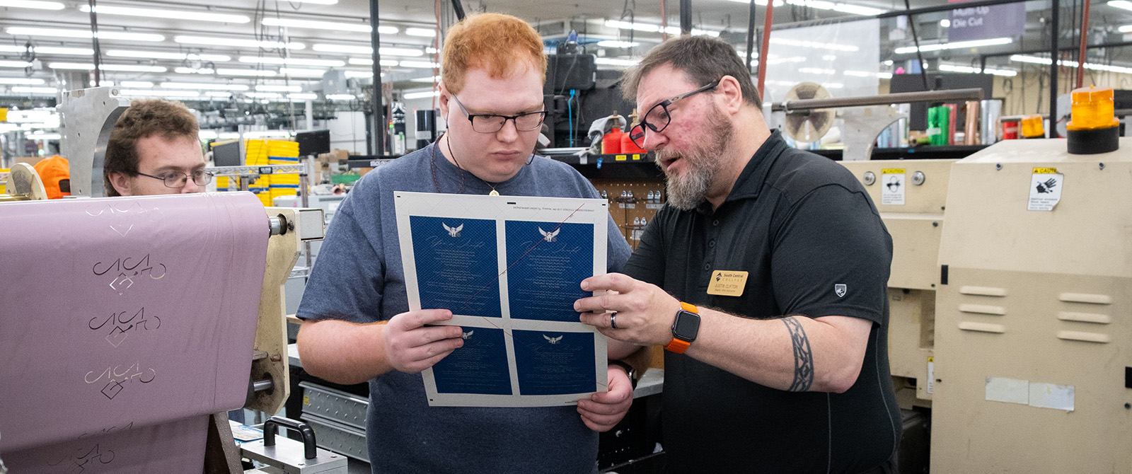 Student and instructor looking at the output of a digital printer in a print lab.