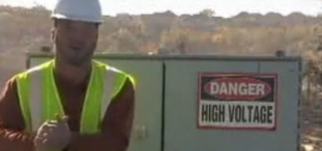 Miner standing in front of a high voltage cabinet with warning sign