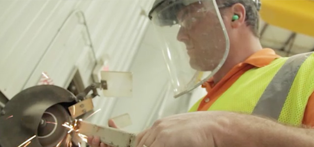 Miner working at a grinder wearing a face shield and hard hat