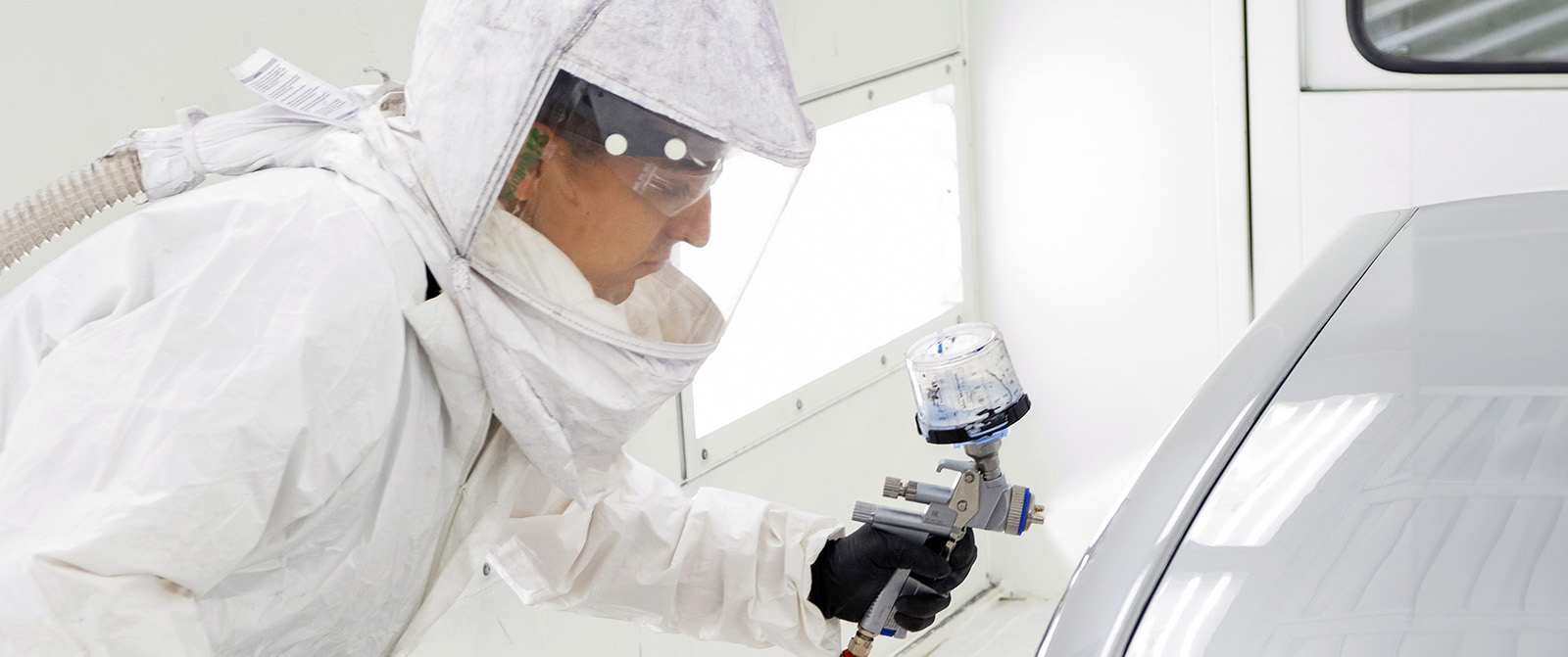 Student in automotive spray booth applying paint.