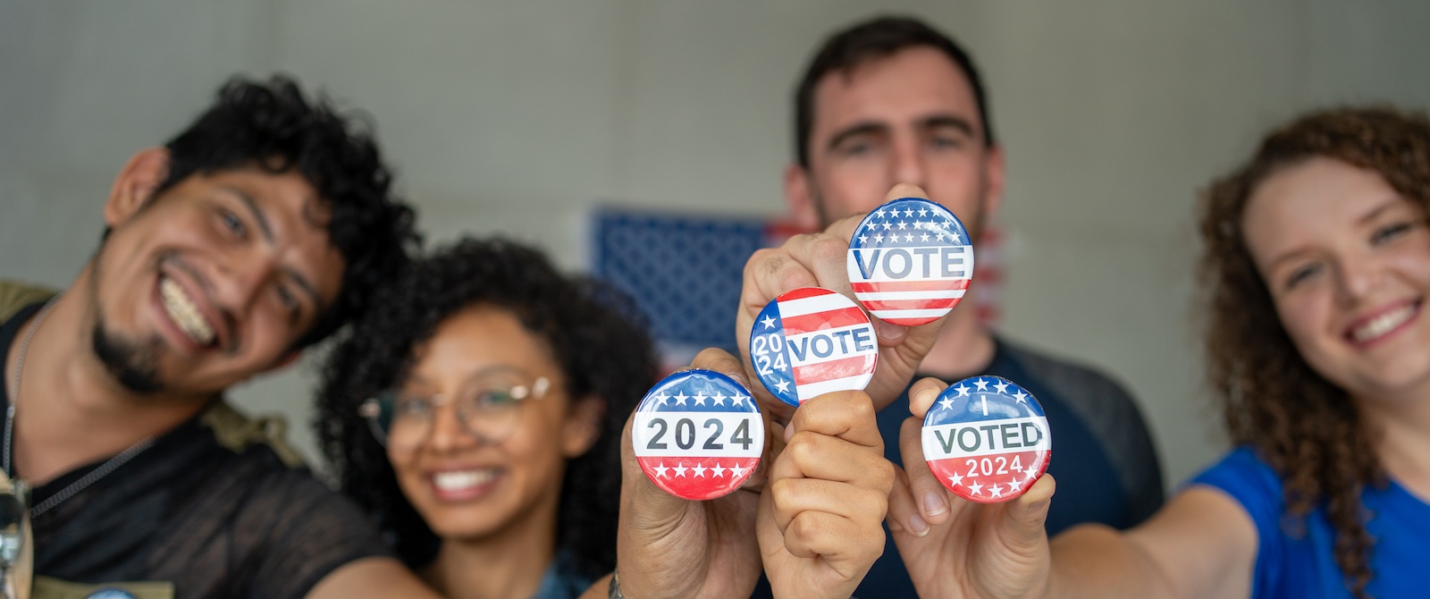 A group of students smiling and each holding up Vote buttons