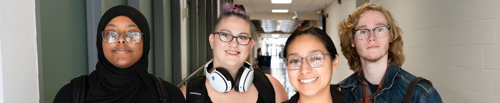 A group of four SCC students standing in the hallway and smiling at the viewer.