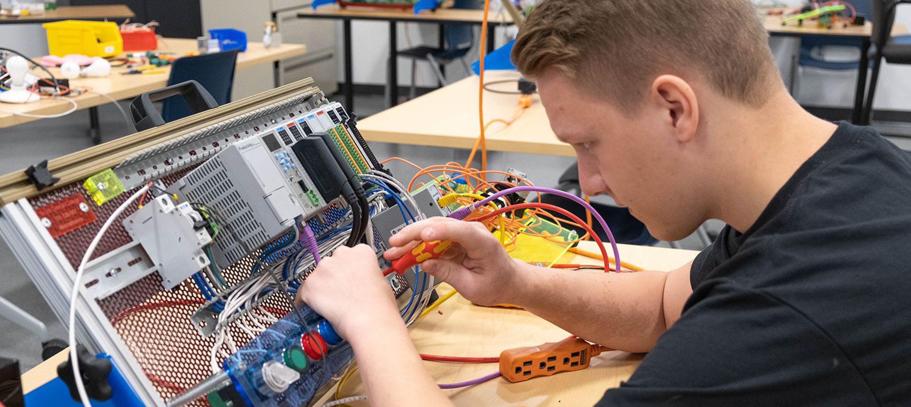 South Central Collage student working on an electronics panel in a lab