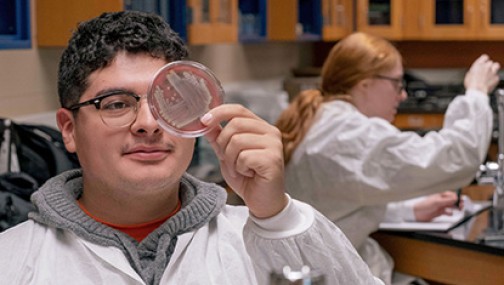 Student holding an experiment container in a biology lab